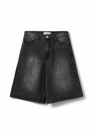 Sorte denimbukser med forreste knap, bæltestropper og fem-lomme-design, der viser en let falmet tekstur på stoffet.