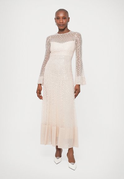 Duga haljina boje breskve sa prozirnim, točkastim slojem, rukavima u obliku zvona i lepršavom suknjom. Nosena uz bijele cipele s oštrim vrhom.