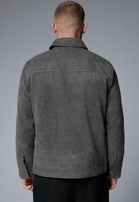 Chaqueta de ante gris con cuello, mangas largas y puños abotonados. Textura suave con un diseño simple y sin patrones o acentos visibles.