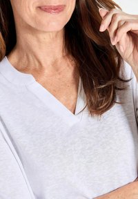 Weißes V-Ausschnitt-T-Shirt mit kurzärmeligen, aus weichem, leichtem Material. Verfügt über eine lässige Passform und eine dezente Textur.