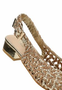 Sandalia trenzada marrón y metálica con un tacón bajo, que presenta patrones intrincados, una correa de tobillo segura y una superficie texturizada.