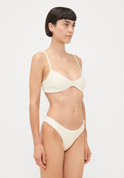 Bikini côtelé crème avec de fines bretelles réglables ; le haut a un décolleté arrondi et le bas présente un design à jambes haute.