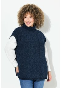 Maglione a girocollo in maglia blu navy con maniche corte, tessuto testurizzato e vestibilità ampia. Indossato sopra una camicia bianca, abbinato a jeans blu.