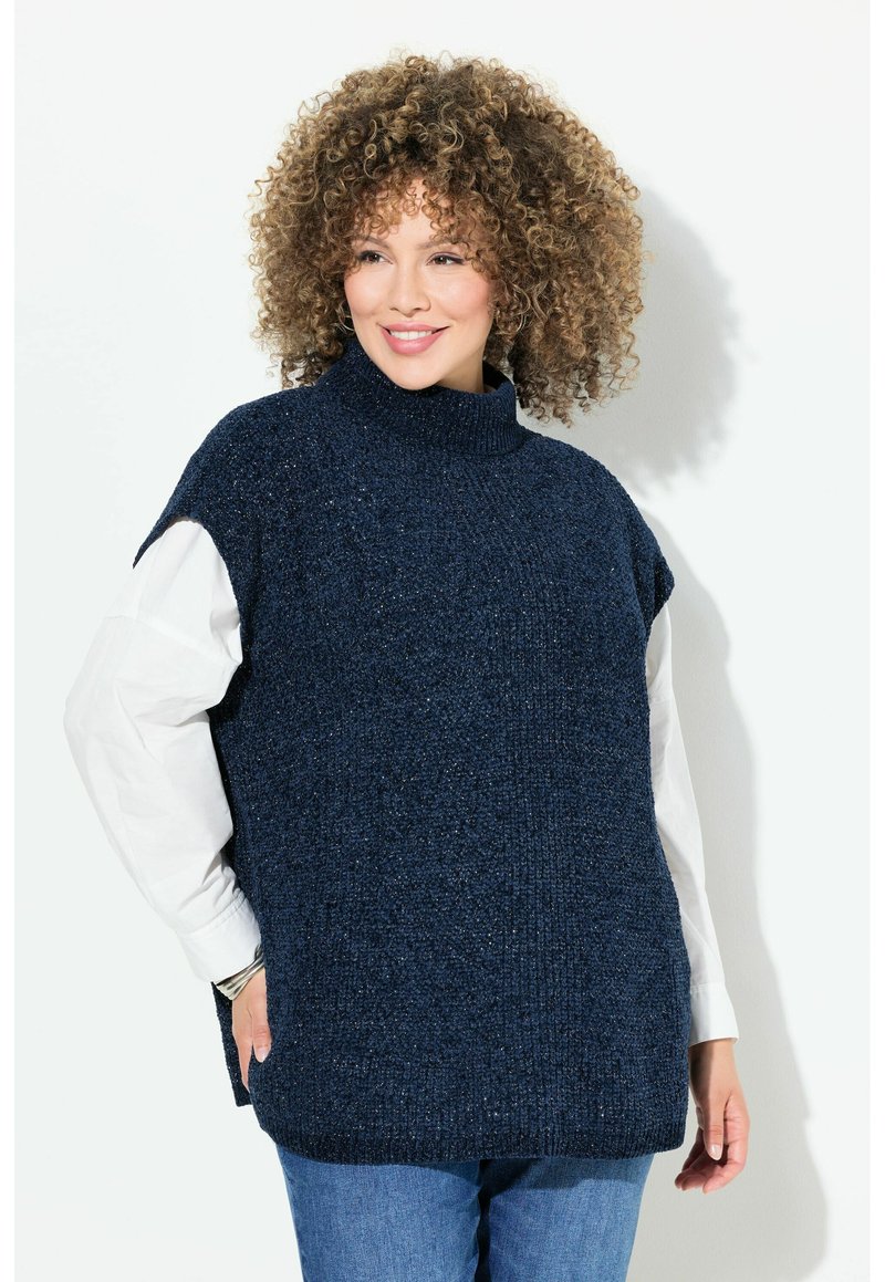 Maglione a girocollo in maglia blu navy con maniche corte, tessuto testurizzato e vestibilità ampia. Indossato sopra una camicia bianca, abbinato a jeans blu.