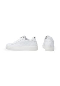 White quilted sneakers with a low profile, round toe, and rubber sole. Features a lace-up front and a pull tab on the heel.