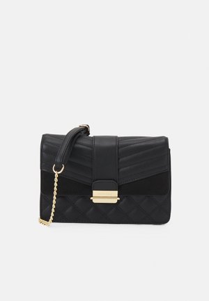 Sort quiltet crossbody-taske med guld kædedor og guld lukning på en hvid baggrund.