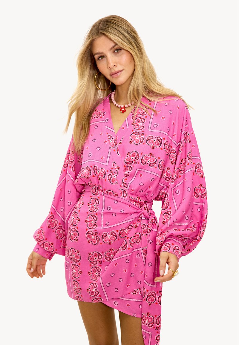 Robe portefeuille imprimée paisley rose avec manches longues, col en V et ceinture nouée. Présente des motifs complexes dans différentes nuances de rose et de rouge.