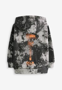 Kapucnis pulóver fekete és szürke tie-dye mintával. Narancssárga nyomtatott szöveggel és ikonokkal rendelkezik, puha tapintású és szabványos fazonú.