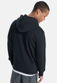 Schwarzes Kapuzensweatshirt aus weichem Material, mit lässigem Schnitt, Rippbündchen und einer verstellbaren Kapuze. Rückansicht gezeigt.