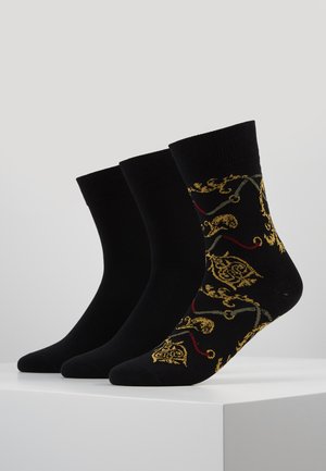 Svarta ankelstrumpor med en enfärgad design, tillsammans med en som har intrikata blomster mönster i guld, röd och grön på en svart bakgrund.