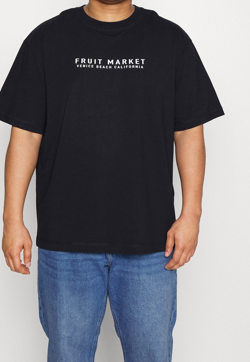 T-shirt in cotone nero con la scritta "FRUIT MARKET VENICE BEACH CALIFORNIA" stampata in bianco, caratterizzata da una vestibilità ampia e maniche corte.
