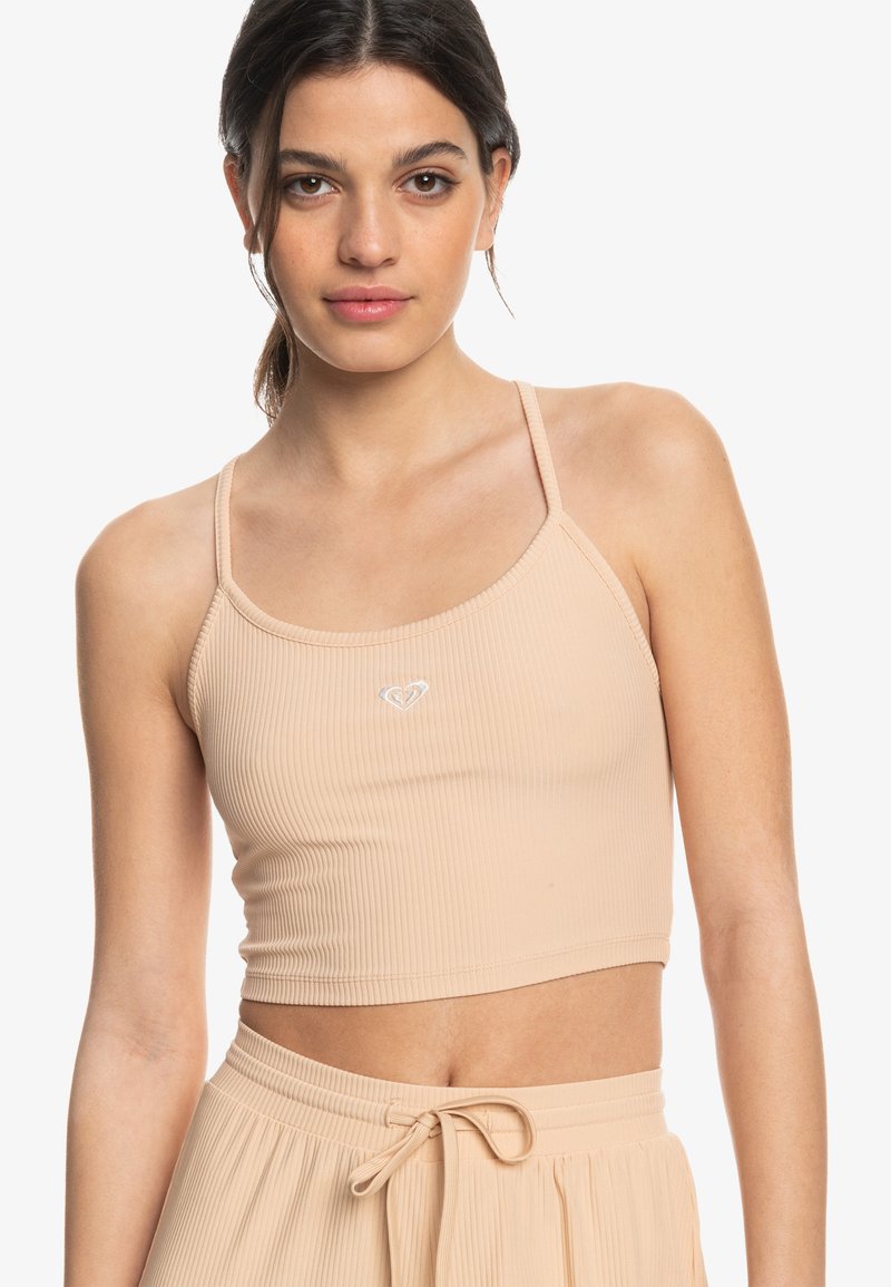 Ribbed beige crop top with thin straps and a small logo at the center, featuring a fitted design and smooth texture.