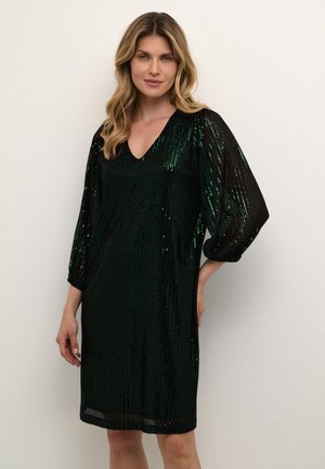 Korte groene jurk met pailletten, een V-hals en driekwart pofmouwen. De stof heeft een getextureerde glans en valt net boven de knie.
