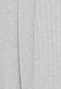 Tessuto grigio lavorato a maglia con texture a coste, caratterizzato da linee verticali e una finitura liscia. Sono visibili sezioni di tessuto sovrapposto.