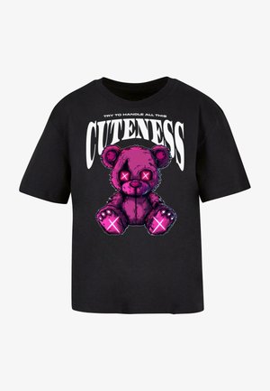 Sort t-shirt med et grafisk motiv af en lyserød teddy-bjørn med X-formede øjne, med teksten "PRØV AT HÅNDTERE AL DENNE SØDME."
