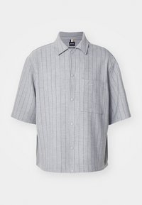 Cămașă cu mânecă scurtă și nasturi, de culoare gri deschis, cu dungi verticale, buzunar pe piept și logo brodat. Fabricată dintr-un material fin și ușor.