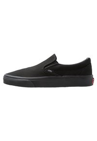 Chaussure slip-on noire en toile avec semelle en caoutchouc. Présente des accents élastiques sur les côtés et une étiquette logo Vans sur le côté. Texture lisse, design minimaliste.