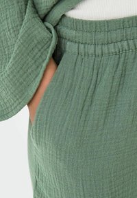 Grønn teksturert stoffbukse med løs passform, med en samlet elastisk midje og sidelomme. Myk, pustende og uformell design.