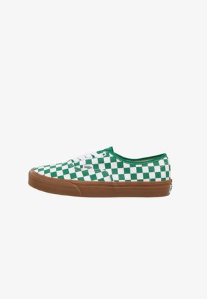 Zapatilla Vans de caña baja con patrón de tablero de ajedrez verde y blanco, cordones blancos y suela de goma marrón sobre fondo blanco.
