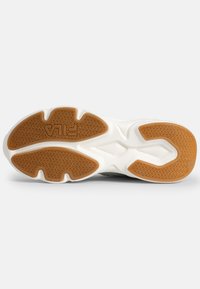 Sula av en sneaker med en gummibotten med ett fiskbensmönster, en vit mellansula och bruna detaljer. Varumärkeslogotyp synlig.