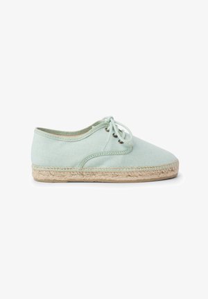Espadrille en toile vert clair avec un design à lacets, bout rond et semelle en corde de jute. Présente des accents brodés le long du bord supérieur.