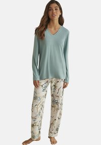 Haut bleu clair à manches longues et col en V associé à un pantalon blanc orné d'un motif floral et de grues. Tissu doux, coupe décontractée, légère brillance.