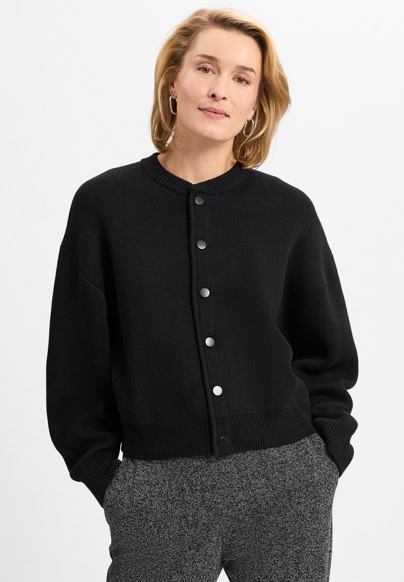 Schwarzer Cardigan mit rundem Ausschnitt, Knopfverschluss und geripptem Saum. Hergestellt aus strukturiertem Strickstoff; hat überschnittene Schultern und eine lässige Passform.