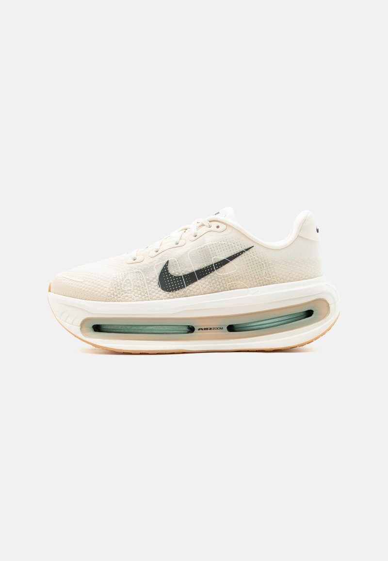 Ανοιχτό μπεζ αθλητικό παπούτσι Nike Air Zoom με μαύρο λογότυπο swoosh, επάνω μέρος από δίχτυ και παχιά μαλακή σόλα με ορατή μονάδα αέρα.