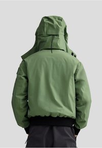 Veste verte isolée avec un col haut, une capuche réglable, des poignets élastiques et un ourlet côtelé ; fabriquée en tissu lisse et résistant à l'eau.