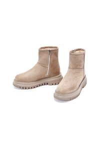 Botines beige de ante suave, con cremallera lateral, forro de felpa y suela de goma gruesa y estriada.