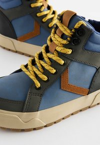 Niebieskie i szare sportowe buty wysokie na sznurówki z żółtymi sznurówkami, brązowymi akcentami, teksturowanym materiałem i wzorzystą gumową podeszwą. Posiada okrągłe oczka.