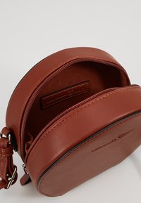 Borsa a tracolla rotonda in pelle marrone con apertura con zip e tasca interna. Presenta una superficie texturizzata e una tracolla regolabile.