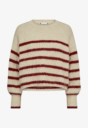 Bežinis juostuotas megztinis su raudonomis horizontaliomis linijomis. Turi siaurėjantį audinį, apvalią iškirptę ir priglundančias rankoves. Apima užsegimo mygtukų detales.