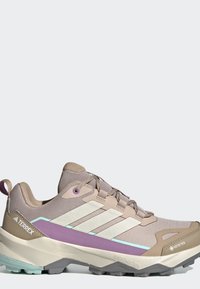 Beige ja violetti Adidas Terrex -polkujuoksukenkä, jossa on GORE-TEX, valkoiset raidat ja teksturoidulla pohjalla ulkokäyttöön.
