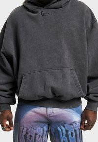 Felpa grigia in cotone con tasca frontale, polsini a costine e cappuccio con coulisse. Presenta un ricamo discreto del logo sul petto.