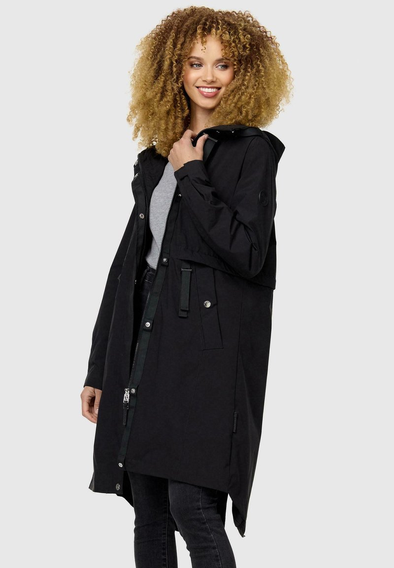 Chaqueta impermeable negra con capucha, cierre de cremallera y cintura ajustable. Presenta bolsillos laterales y mangas largas. Textura suave.