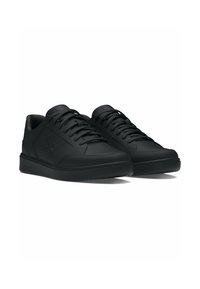 Black sneakers featuring a smooth leather upper, flat laces, padded collar, and a minimalist design with a subtle logo on the side.