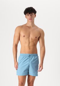 Shorts de bain bleu clair avec une taille élastique, d�étail de cordon de serrage et une texture simple et lisse. Aucun motif ni accent présent.