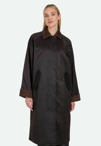 Brun nyloncoat med et kordfløjskrave og mansjetter, der har sidelommer og en løs pasform. Glat tekstur med minimal detaljering.