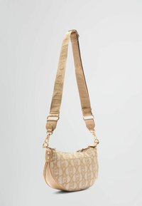 Sac hobo en tissu beige avec motif embossé, ferrures dorées et bandoulière réglable. Caractérisé par une forme incurvée et une fermeture éclair.