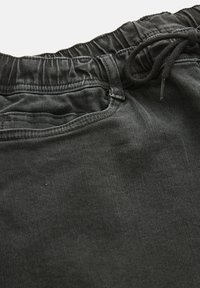 Svarta jeansshorts med resår i midjan och dragsko, platta framfickor och en slät textur med subtila blekningsdetaljer.