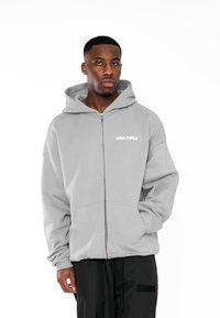 Felpa grigia con zip, dotata di tasca frontale e logo "MULTIPLY" in bianco; presenta una vestibilità comoda e un grande cappuccio per il massimo comfort.