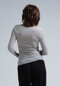 Langärmliges graues T-Shirt mit tailliertem Design, aus weichem Stoff. Verfügt über Raglanärmel und eine glatte, leicht strukturierte Oberfläche.