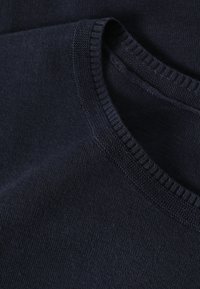 Nahaufnahme eines dunkel marineblauen, gestrickten Pulloverkragens mit detaillierter Rippenstrickerei und feiner Stoffstruktur.