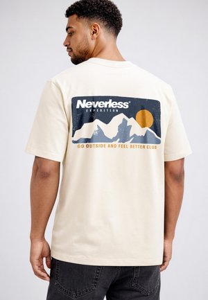 Mann trägt beige T-Shirt mit Berggrafik, orangefarbener Sonne und Text „Neverless Expedition“ und „Go Outside and Feel Better Club“ auf dem Rücken.