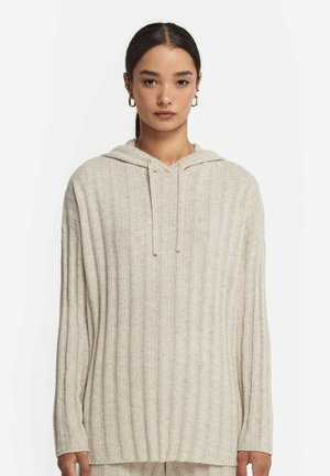 Ljus beige ribbad hoodie med långa ärmar, en framficka för händerna och justerbara dragsnören på huva. Mysig och mjuk textur.