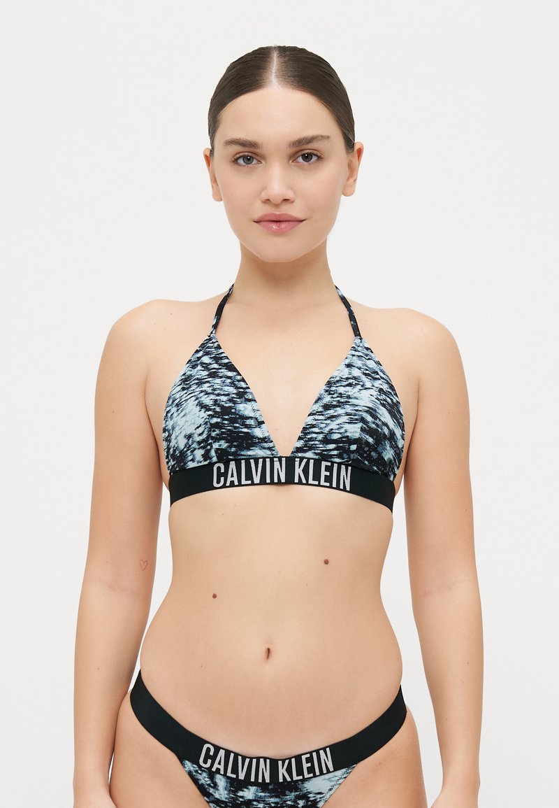 Calvin Klein bikini-set met een zwart en blauw abstract patroon, driehoekige top met halterbinders en mid-rise onderbroek met logo-banden.