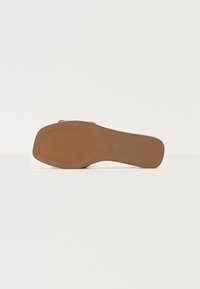 Brązowa podeszwa buta z teksturowanym gripem, lekko wygięty kształt, płaski design oraz minimalne logo na górnej stronie.