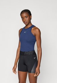 Marineblå ærmeløs atletisk top med rund halsudskæring og logo, parret med sorte kompressionsshorts med en struktureret sidelap og logo på taljen.