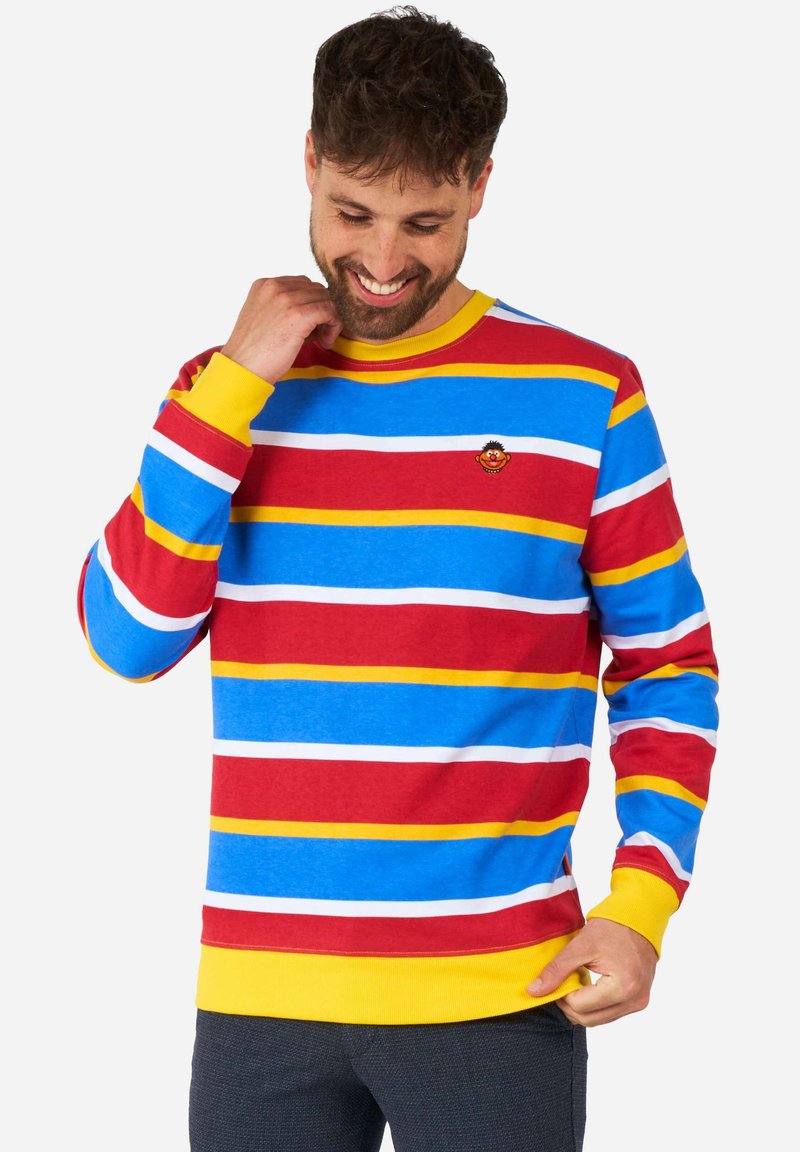 Sudadera multicolor con rayas horizontales rojas, azules, amarillas y blancas, puños acanalados y un pequeño logo de personaje bordado en el pecho.